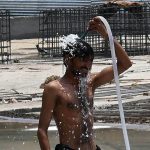 A worker bathes at his workplace in a bid to escape the intense summer heat, as rising temperatures continue to make life difficult for outdoor labourers and daily wage workers
