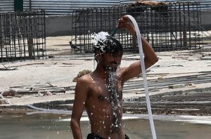 A worker bathes at his workplace in a bid to escape the intense summer heat, as rising temperatures continue to make life difficult for outdoor labourers and daily wage workers