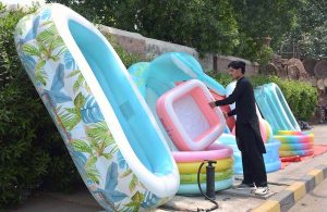 A vendor displays colorful inflatable swimming pools for children at a roadside stall, attracting customers seeking ways to beat the summer heat amid rising temperatures.