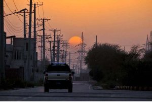 A memorizing view of sunset as golden hues of the setting sun illuminate the skyline and roadside structures create a captivating urban panorama.