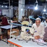 Workers are busy sewing clothes on machines at a local factory