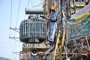 WAPDA worker fixing power transformer on an electric pole.