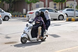 Three women are on their way on electric scooty at Club Chowk.