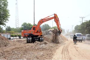 A worker fills a trench with the help of machinery after laying a sewerage pipeline at Piran Ghaib Road.