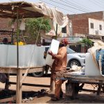 A laborer unloads large ice blocks from a tricycle loader at a roadside vendor stall as demand for ice increases amid scorching summer temperatures in the city