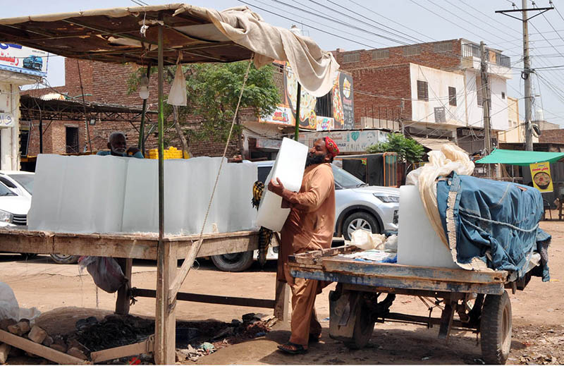 A laborer unloads large ice blocks from a tricycle loader at a roadside vendor stall as demand for ice increases amid scorching summer temperatures in the city