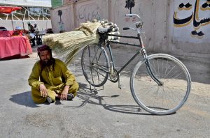 A bicycle vendor rests in the shade beside the roadside to escape the scorching summer heat while waiting for customers along Joint Road in the provincial capital.