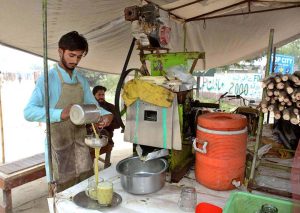A vendor serves freshly extracted sugarcane juice to customers as soaring temperatures boost demand for cold and refreshing beverages to relief across the city.