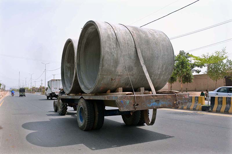 A tractor trolley passes through the old Shujabad road loaded with heavy concrete pipes
