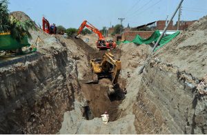 Heavy machinery and workers are engaged in deep excavation work for a major sewerage infrastructure project, aimed at improving the city's drainage and sanitation system under ongoing urban development initiatives.