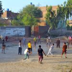 A group of youngsters playing a friendly volleyball match at an open ground in a village area