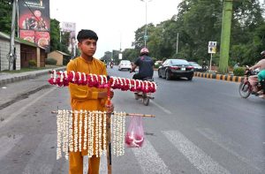 A young vendor sells fresh flower garlands and bracelet (Gajras) along University Road.
