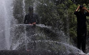 Youngsters cool off by bathing in water gushing from a leaking supply pipeline to seek relief from the intense summer heat gripping the city.