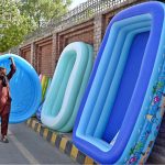 A vendor arranges colourful plastic swimming pools for children along a roadside to attract the customers at Chandka Medical College Road