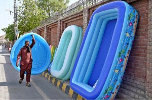 A vendor arranges colourful plastic swimming pools for children along a roadside to attract the customers at Chandka Medical College Road