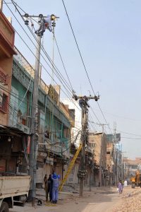 MEPCO staffers perform maintenance and repair work on electricity distribution lines atop power poles during an infrastructure improvement operation in the city.