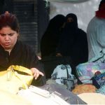 A woman selects used handbags at Empress Market