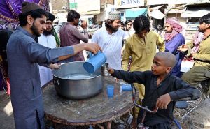 Volunteers distribute cold water at Jinnah Bagh Chowk during a hot day in the city, providing relief to passersby to escape the heatwave amid rising temperatures.
