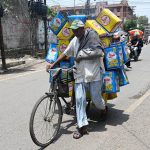 An elderly man with his arm in a plaster cast rides a bicycle on Hall Road as he heads to sell tin cans to earn a livelihood