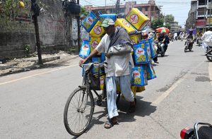 An elderly man with his arm in a plaster cast rides a bicycle on Hall Road as he heads to sell tin cans to earn a livelihood