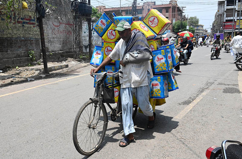 An elderly man with his arm in a plaster cast rides a bicycle on Hall Road as he heads to sell tin cans to earn a livelihood