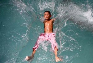 A youngster dives into a swimming pool to get relief from the scorching summer heat in the city.