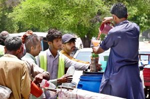 A volunteer distributes juice to commuters and pedestrians to help them cope with the intense summer heat at Thandi Sarak.