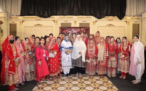 Brides are sitting on stage during a mass marriage ceremony arranged by the Madina Foundation to unite 35 deserving couples at a local marriage hall