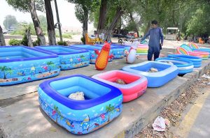 A vendor displays inflatable water pools for children at Latifabad to attract customers during the summer season.