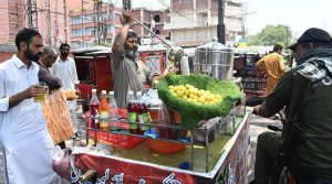 A street vendor selling lemon malt cold drinks at a roadside stall as people look for relief from the scorching heat in the city.