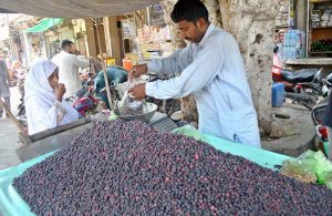 A female customer purchasing seasonal fruit 'Falsa' from a vendor at local market.