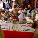 People enjoy lassi as a vendor serves the traditional yogurt-based drink to attract customers during hot weather in the city