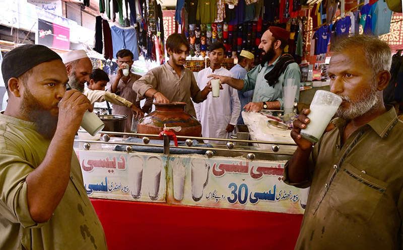 People enjoy lassi as a vendor serves the traditional yogurt-based drink to attract customers during hot weather in the city