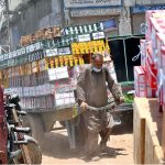 A laborer pulls a heavily loaded handcart through a busy market street, as daily wage workers continue to play a vital role in the city's local trade and transport