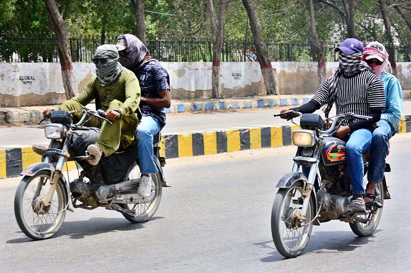 A motorcyclists on the way cover their face with piece of cloth to protect from direct sunlight during hot weather in the city