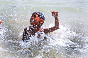 A youngster takes a bath in a canal to seek relief from the intense summer heat in the city
