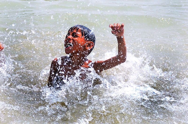 A youngster takes a bath in a canal to seek relief from the intense summer heat in the city
