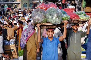 Daily wagers carrying the vegetables basket on their head as people selecting and purchasing the vegetables at Fruit and Vegetable market in the Provincial Capital.