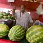 A vendor displays watermelon juice outside the railway station to attract customers