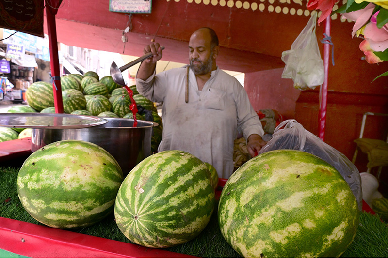 A vendor displays watermelon juice outside the railway station to attract customers