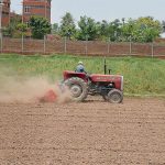 A farmer ploughs and prepares agricultural land with a tractor for the upcoming crop season on the outskirts of the city