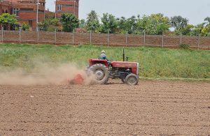 A farmer ploughs and prepares agricultural land with a tractor for the upcoming crop season on the outskirts of the city