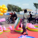 A vendor arranges colourful inflatable paddling pools, rubber rings and bunny toys at a roadside stall as customers show keen interest in the cooling products, with demand for children's summer accessories surging amid the intense heat gripping the city