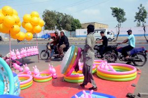 A vendor arranges colourful inflatable paddling pools, rubber rings and bunny toys at a roadside stall as customers show keen interest in the cooling products, with demand for children's summer accessories surging amid the intense heat gripping the city