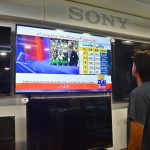 A shopkeeper keeps his eyes fixed on a television screen at his shop while watching Finance Minister Muhammad Aurangzeb present the Federal Budget 2026–27
