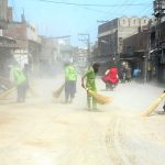 Sanitary workers sweep sand and debris from a road at Doulat Gate after the conclusion of the 10th Muharram (Ashura) procession, as a dust cloud rises during the post-procession cleanliness operation in the city