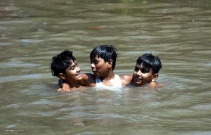 Youngsters cool off by bathing in a canal to seek relief from the scorching summer heat.