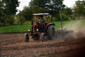 A farmer ploughs and prepares agricultural land with a tractor for the upcoming crop season on the outskirts of the city