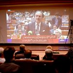 Members of the business community listen to the Federal Budget 2026–27 speech by Finance Minister Muhammad Aurangzeb, broadcast live on a multimedia screen at the Karachi Chamber of Commerce & Industry (KCCI) Auditorium