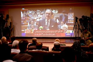 Members of the business community listen to the Federal Budget 2026–27 speech by Finance Minister Muhammad Aurangzeb, broadcast live on a multimedia screen at the Karachi Chamber of Commerce & Industry (KCCI) Auditorium